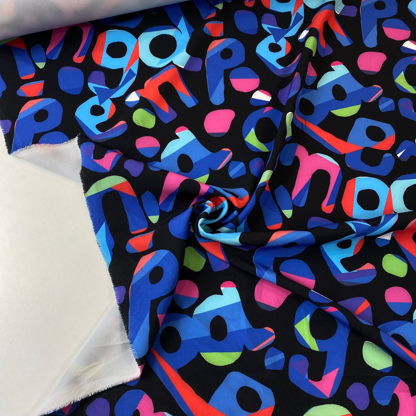 Tejido de punto interlock negro con letras de colores.