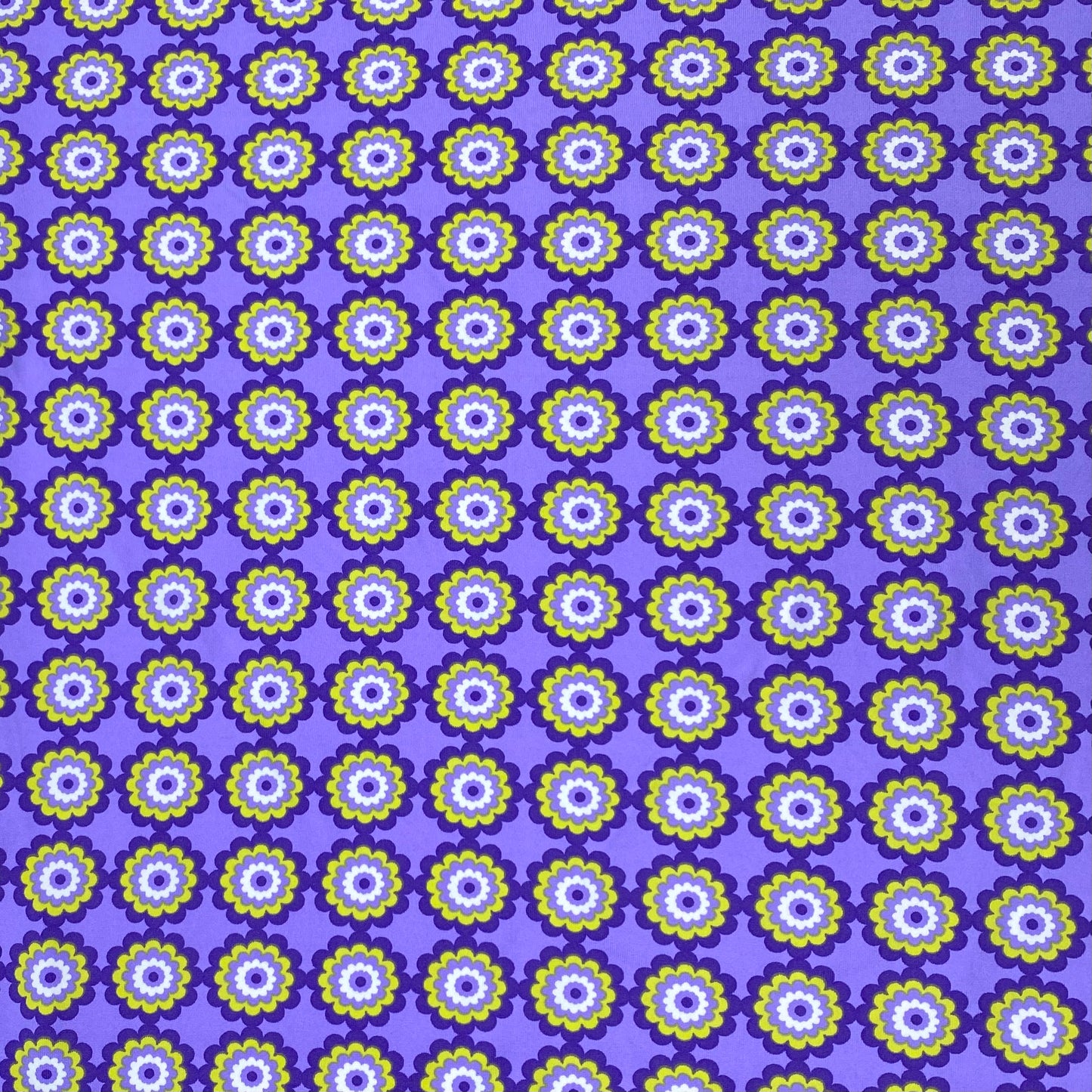 Tejido de punto lycra con fondo morado y flores verdes y lilas.