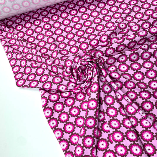 Tejido de punto lycra con fondo rosa y flores rosas y moradas.