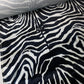 Tejido aterciopelado con estampado de cebra en blanco y negro.