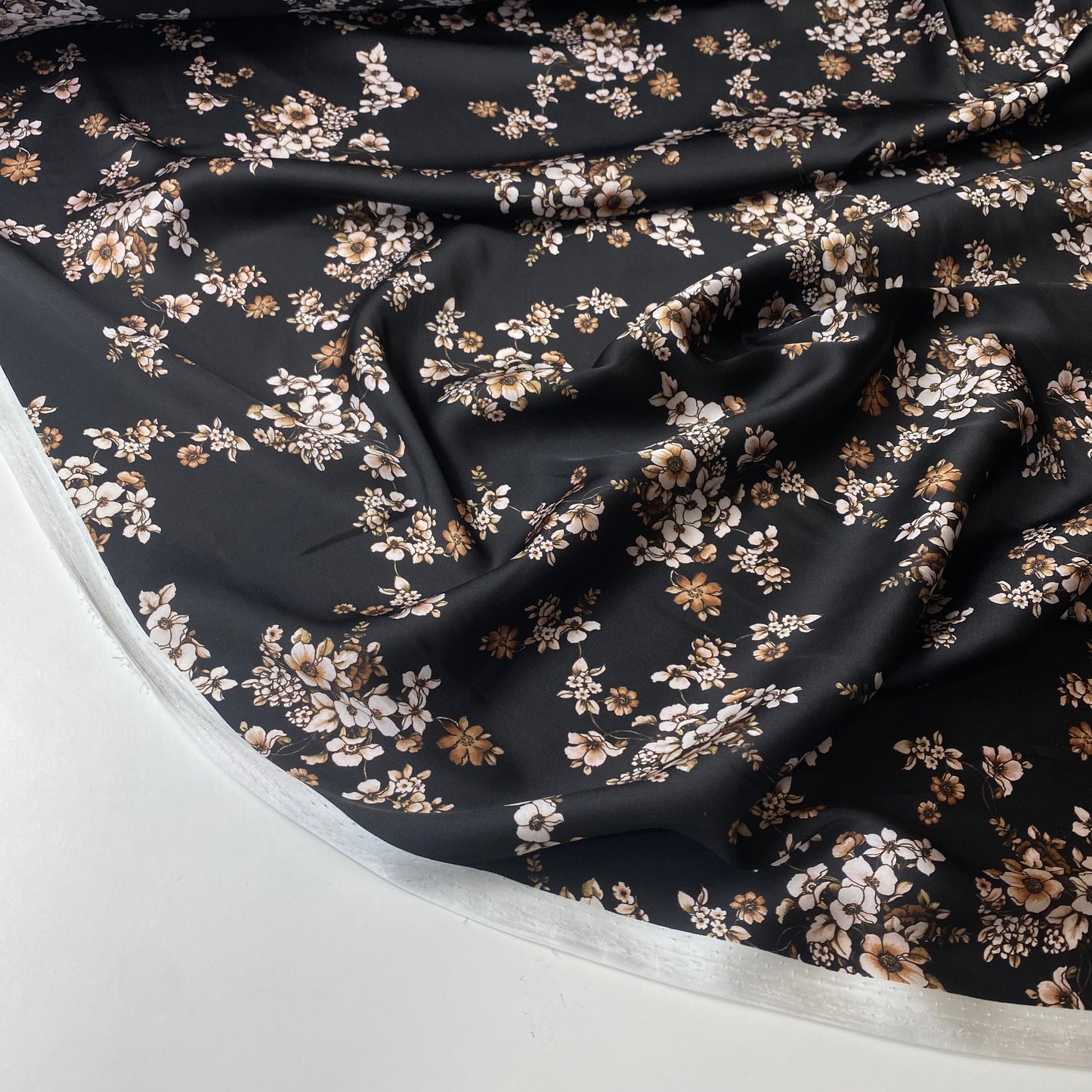 Satén negro con flores blancas y beige.
