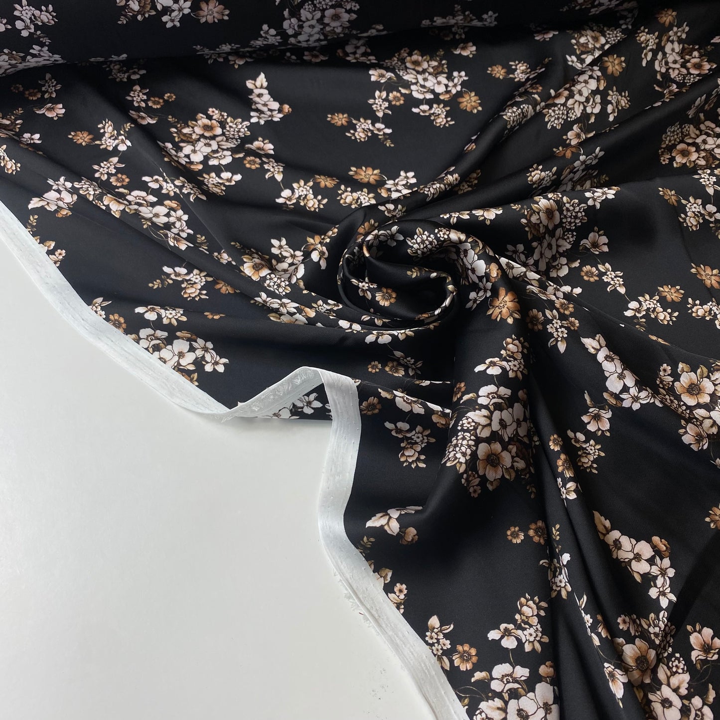 Satén negro con flores blancas y beige.