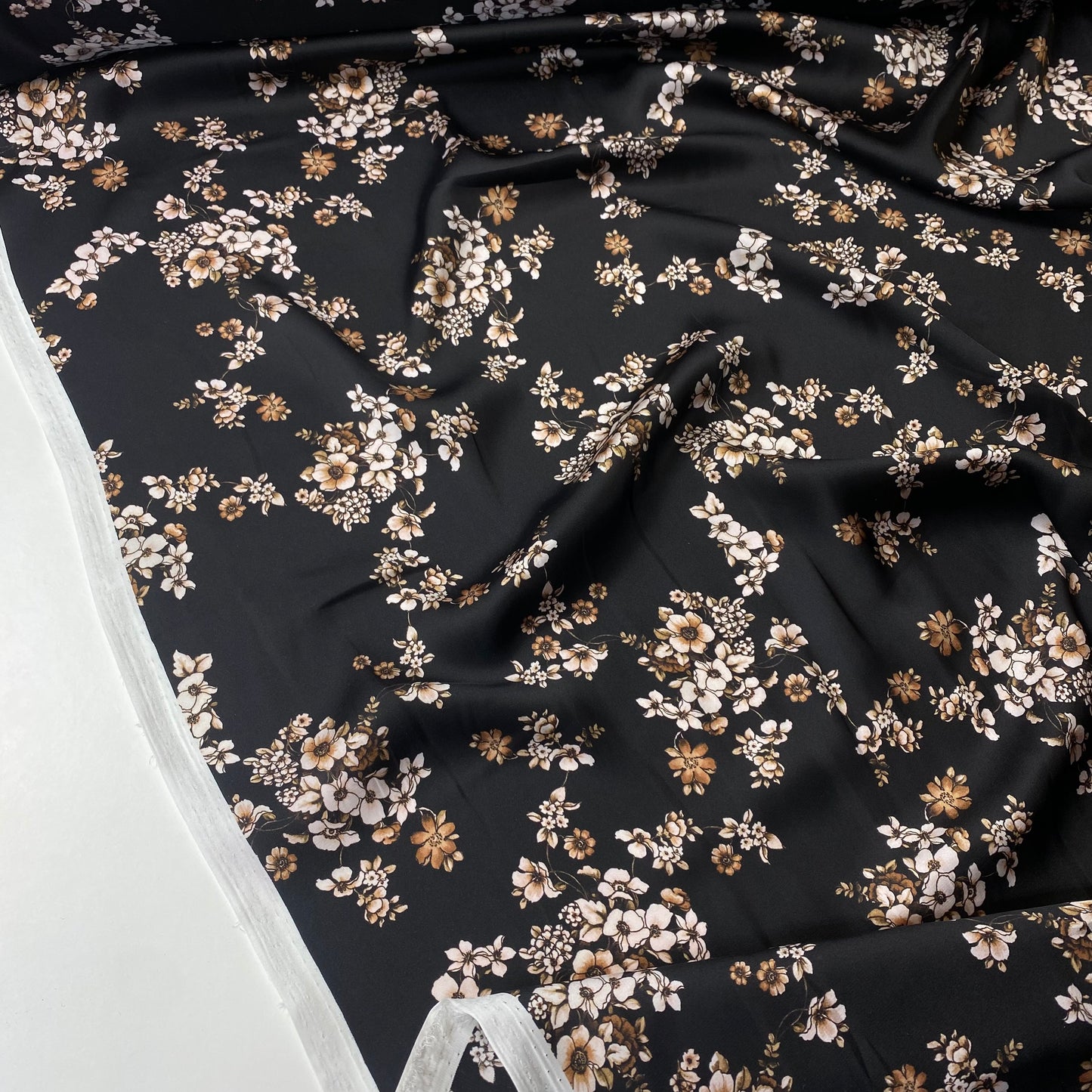 Satén negro con flores blancas y beige.